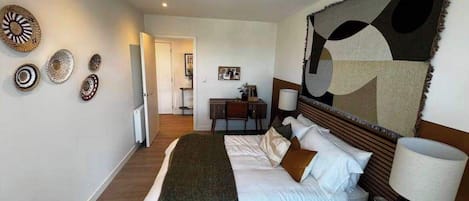 A hotel room with a bed, bedside table, lamp, and wall decor.