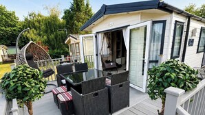 Un espacio al aire libre techado con una mesa, sillas y plantas en macetas, además de una silla colgante.
