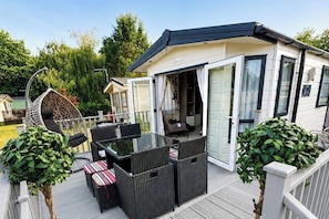 A covered outdoor area with a table and chairs, a hanging chair, and potted plants. - StaticCaravan-6Berth-DogFriendly (Northampton)