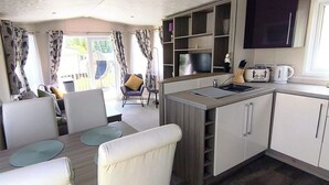 Cocina compacta con comedor, televisor y vistas al exterior.