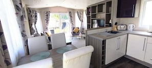 A compact kitchen with a dining area, a TV, and a view of the outside. - StaticCaravan-6Berth-DogFriendly (Northampton)