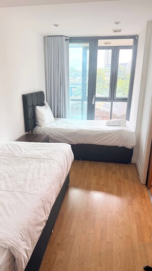 A bedroom with two beds, large windows, and a view of buildings. - Luxury Central London Apartment Paddington (London)