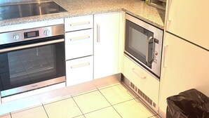 Una cocina con extractor de acero inoxidable, horno empotrado, microondas y refrigerador.