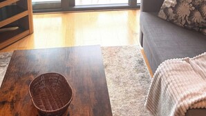 Amplia sala de estar con un gran ventanal corredero que da a un balcón exterior, un sofá, una mesa de centro y un televisor.