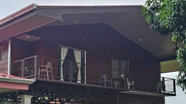 A two-story building with a balcony, a truck parked in front, and a staircase leading to the upper level. - Divina Naturaleza (Fortuna)