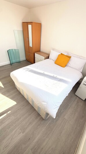 Ein Schlafzimmer mit einem großen Bett, einem Holzschrank, einem Nachttisch und einer Glasschrank.