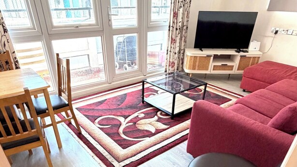 En moderne stue med sofa, fjernsyn og spiseplads med stole og bord.