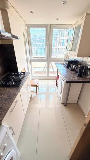 A modern kitchen with a gas stove, a washing machine, and a coffee maker.