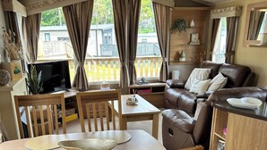 Ein gemütliches Wohnzimmer mit einem braunen Ledersofa, einem Holzesstisch und Stühlen.