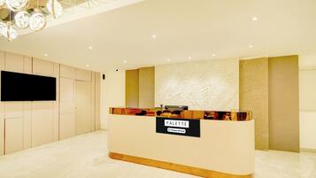 A reception desk with a 'PALETTE' sign, a flat-screen TV, and a modern interior design.
