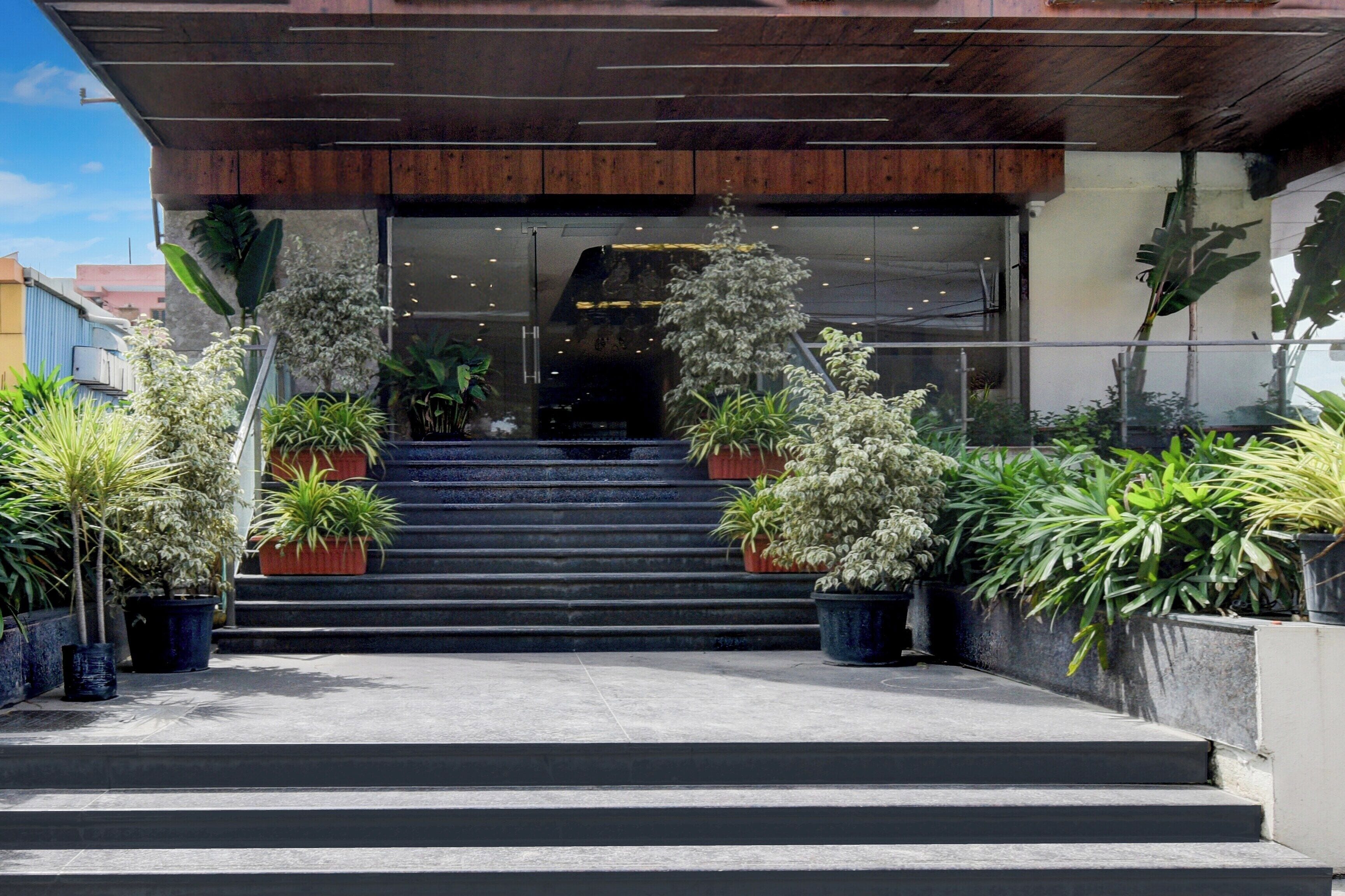Una entrada de edificio con escaleras, plantas en macetas y un diseño moderno.