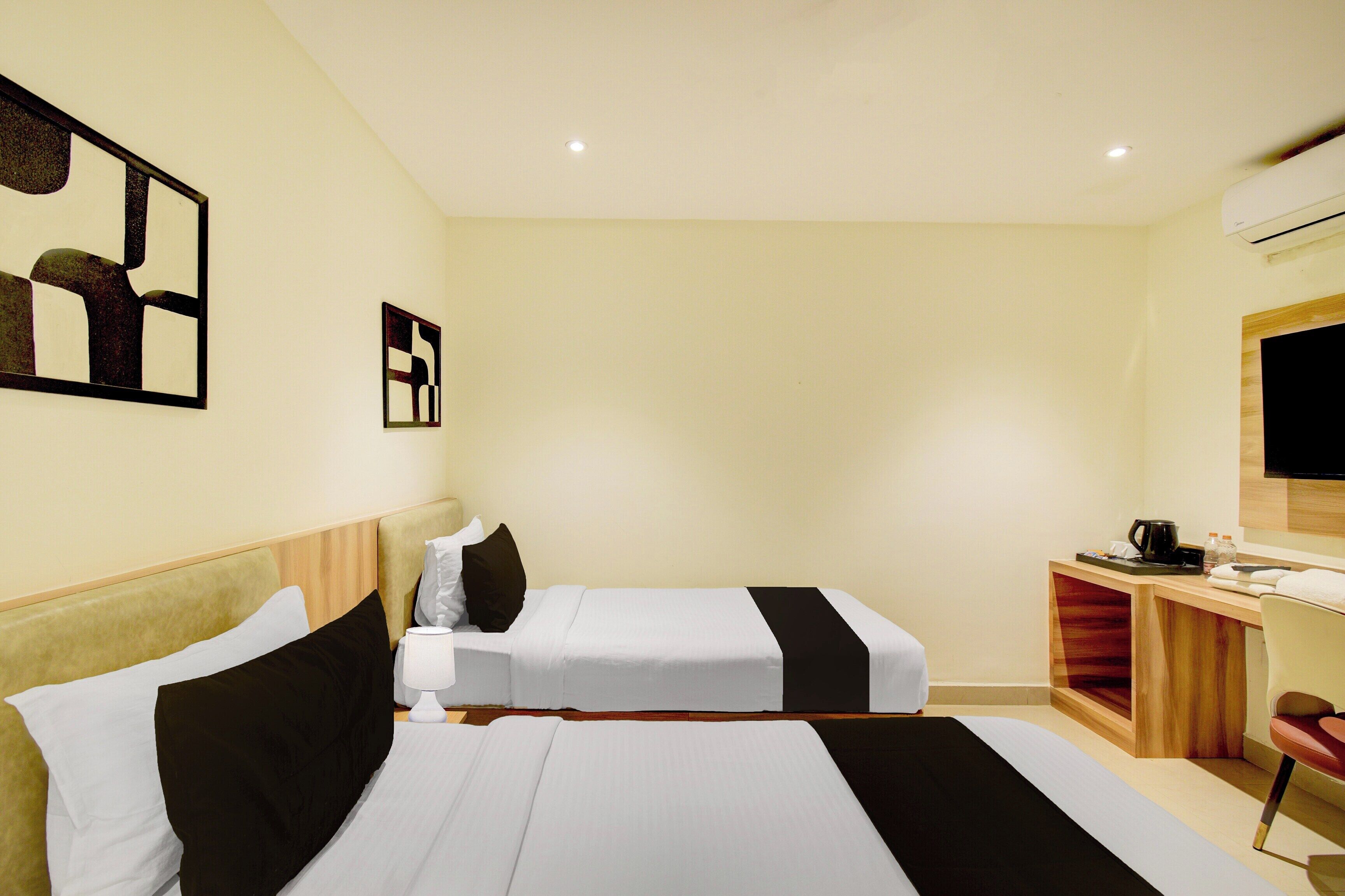 Habitación de hotel con dos camas, un escritorio con silla, televisión y una pequeña kitchenette.