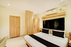 Un dormitorio con cama, armario, mesita de noche y ventana.