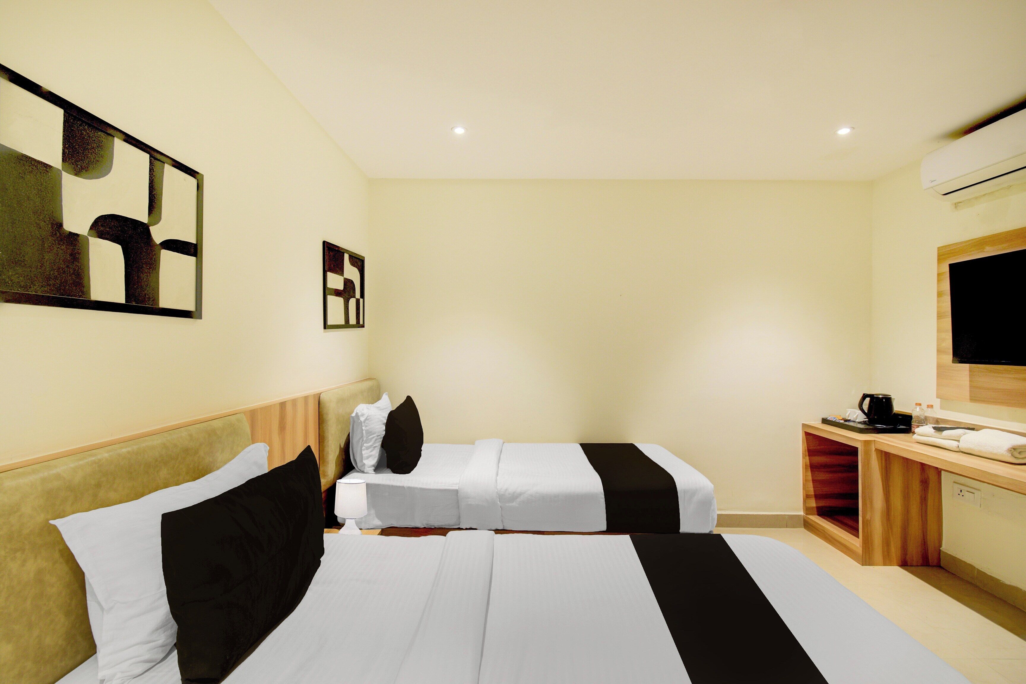 Une chambre d’hôtel avec deux lits, un bureau doté d’un téléviseur à écran plat et une petite kitchenette.