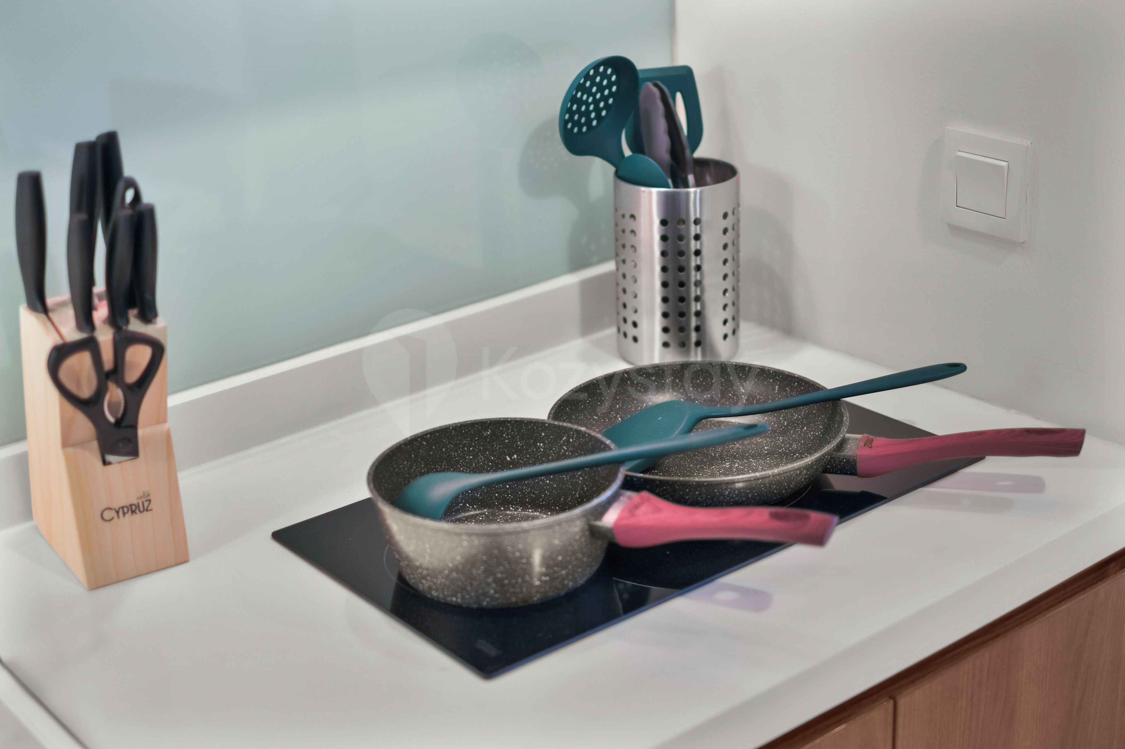 A kitchen counter with a pot, a pan, and a utensil holder.