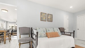 A bedroom with a bed, two chairs, a table, and a door.