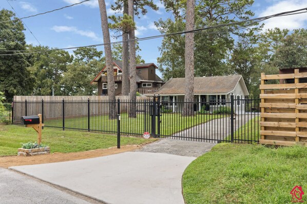 A residential property with a fenced yard, a mailbox, and a driveway leading to a house with a porch.