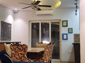 Un comedor con ventilador de techo, equipo de aire acondicionado, puerta de vidrio que da a un espacio exterior y decoración en la pared.