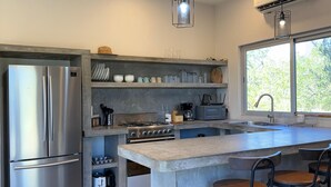A modern kitchen with a stainless steel refrigerator, a built-in oven, a gas stove, and a large island with bar stools. - Casa El Viento: Modern 3-Bedroom Desert & Sea Retreat in El Sargento (El Sargento)