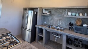 A compact kitchen with a built-in refrigerator, a gas stove, a sink, and a microwave. - Casa El Viento: Modern 3-Bedroom Desert & Sea Retreat in El Sargento (El Sargento)