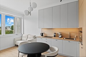 A modern kitchen with a dining area, a coffee maker, and a view of the outdoors. - Zamojska Skyline View Apartment (Lublin)