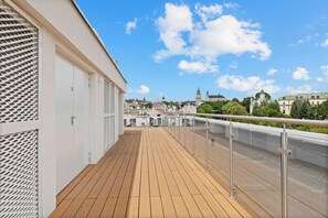 A wooden deck with metal railings, overlooking a cityscape with buildings and a clear sky. - Zamojska Skyline View Apartment (Lublin)