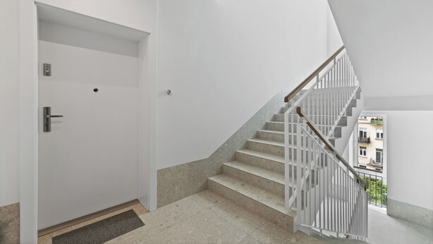 A modern interior with a white door marked '15', a staircase with white railings, and a view of buildings outside. - Zamojska Skyline View Apartment (Lublin)