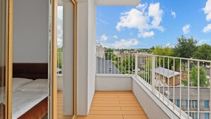 A balcony with a wooden floor and white railing, overlooking a residential area with houses and trees. - Zamojska Skyline View Apartment (Lublin)