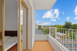 A balcony with a wooden floor and white railing, overlooking a residential area with houses and trees. - Zamojska Skyline View Apartment (Lublin)