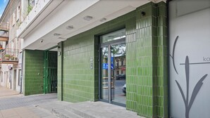 A building with a green tiled facade, a glass door entrance, and a visible sign with a downward arrow. - Zamojska Skyline View Apartment (Lublin)