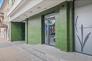 A building with a green tiled facade, a glass door entrance, and a visible sign with a downward arrow. - Zamojska Skyline View Apartment (Lublin)