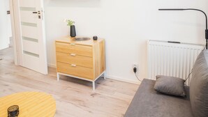 Ein modernes Wohnzimmer mit einem Holzkabinett, einem grauen Sofa, einem kleinen runden Tisch und Wandregalen.