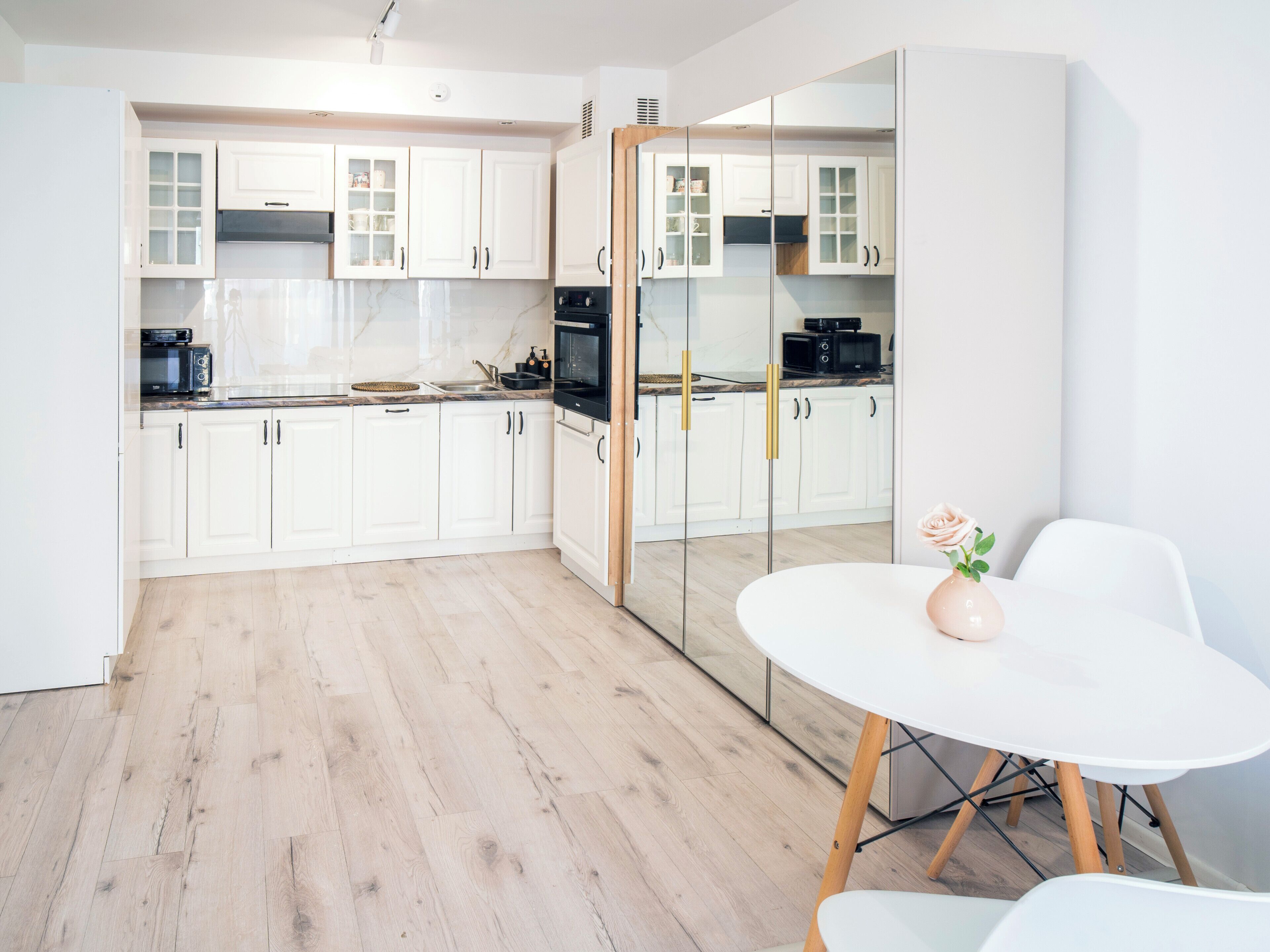 Una cocina moderna con gabinetes blancos, un microondas y una cafetera.