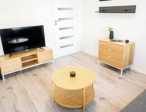 Una sala moderna con televisor de pantalla plana, muebles de madera y una pequeña mesa redonda.