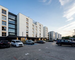 A parking lot with multiple cars and a building with a modern design. - Letnica Baltic Prestige Apartment (Gdańsk)