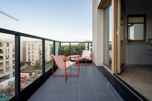A balcony with a table and chairs, a view of buildings, and a kitchen area. - Letnica Baltic Prestige Apartment (Gdańsk)