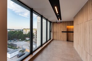 A corridor with large windows, wooden panel walls, and a view of a cityscape. - Letnica Baltic Prestige Apartment (Gdańsk)