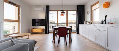 A modern apartment with a dining area, kitchen, living room, and a balcony with a view of the city.