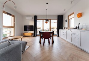 Un apartamento moderno con comedor, cocina, sala de estar y un balcón con vista a la ciudad.