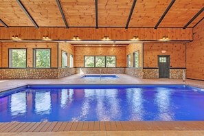 A swimming pool with a stone wall and wooden ceiling, surrounded by windows. - NEW! Jenny Lynn Lodge (Logan)