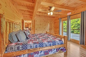 A wooden cabin bedroom with a bed, a ceiling fan, and a view of the outdoors. - NEW! Jenny Lynn Lodge (Logan)