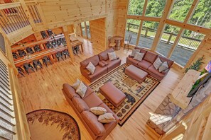 A spacious wooden interior with a large seating area, dining space, and large windows offering a view of the outdoors. - NEW! Jenny Lynn Lodge (Logan)