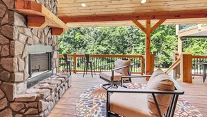 Eine Terrasse im Freien mit Steinkamin, Holzdeck und Sitzgelegenheiten.
