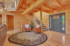 A wooden interior with a staircase, a gray door, and a seating area with a rug. - NEW! Jenny Lynn Lodge (Logan)