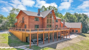 A two-story log cabin with a balcony, stone chimney, and a covered outdoor seating area. - NEW! Jenny Lynn Lodge (Logan)