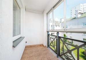 Un balcó amb vista a altres edificis, una finestra i una barana metàl·lica.