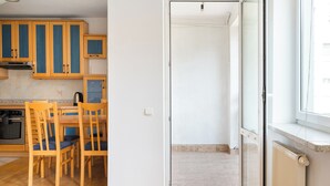 Eine Küche mit Holzschränken, einem Esstisch mit Stühlen und einer Glastür zum Balkon.