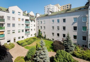 Een meerlaags woongebouw met balkons, een binnentuin met beplanting, en een heldere lucht.