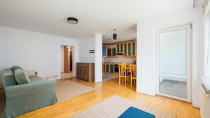 Ein modernes Wohnzimmer mit einer Couch, einem Esstisch mit Stühlen und einer Küchenzeile mit Holzausbau.