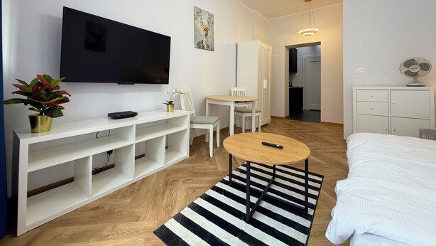 Ein modernes Hotelzimmer mit Flachbildfernseher, Essbereich, Bett und kleinem Tisch.